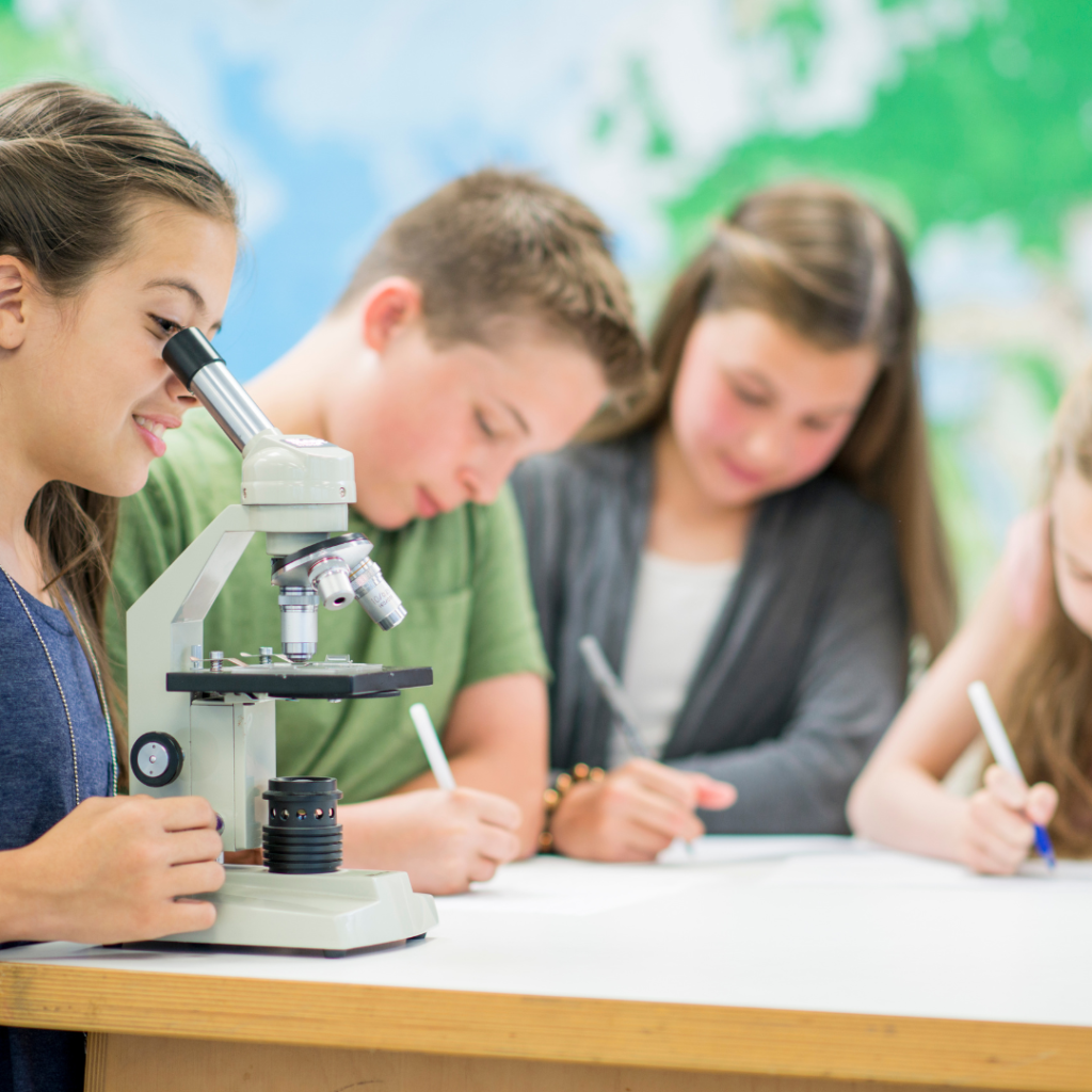 student using microscope while others are writing